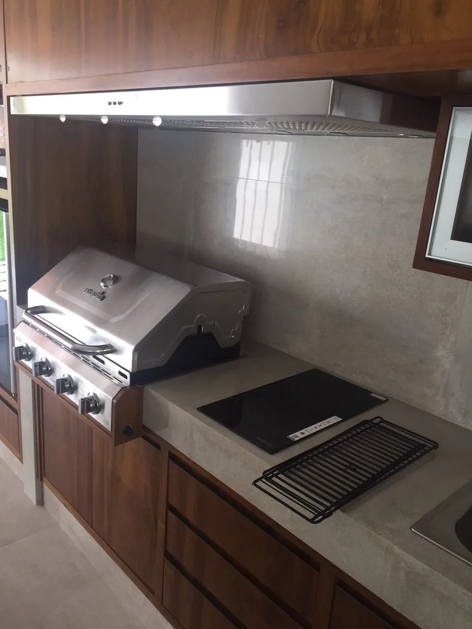 Detalhe da coifa Máxima Integra, com filtros e iluminação sob a marcenaria