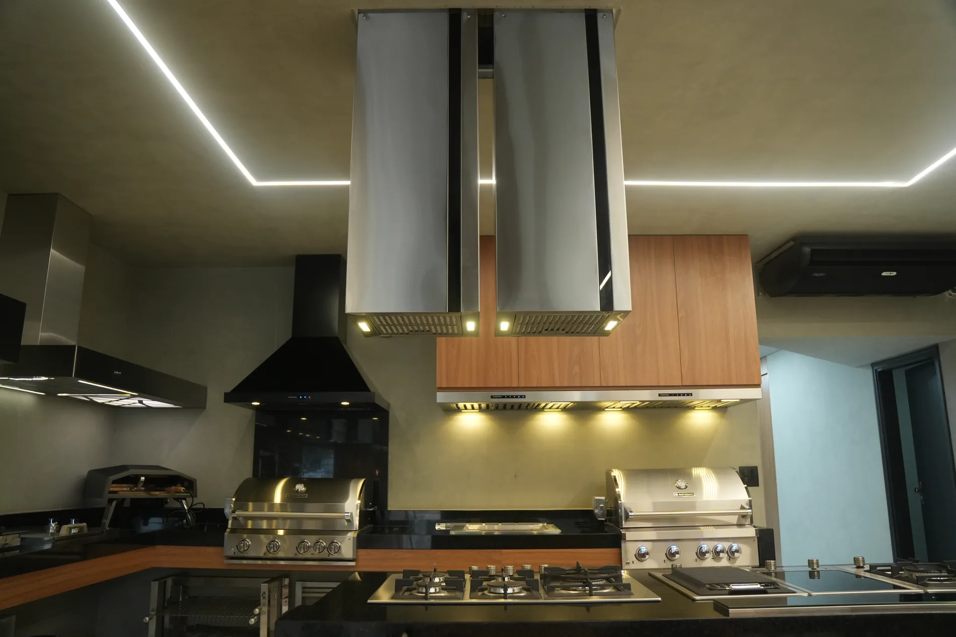 Coifa Máxima Viena de ilha instalada em cozinha com churrasqueira e cooktop